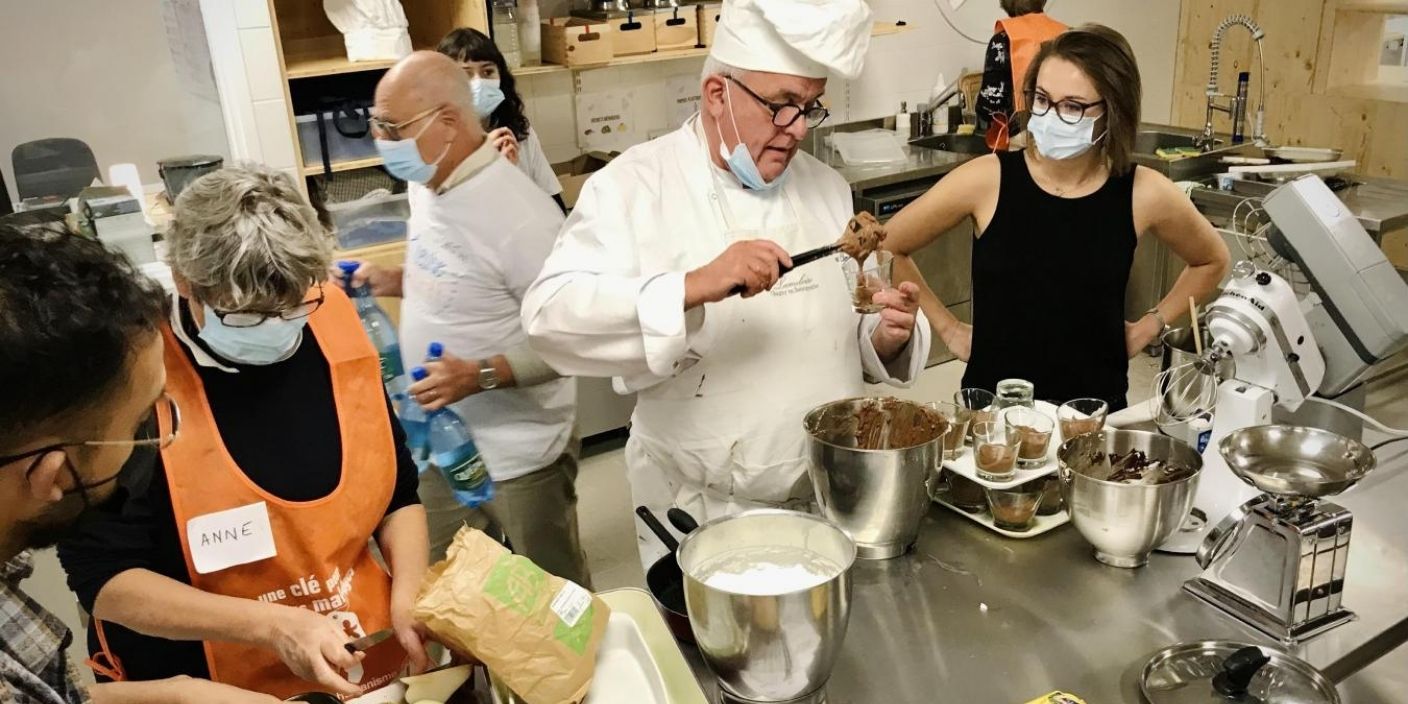 Atelier de cuisine solidaire à Lille, animé par un chef cuisinier avec des bénévoles préparant des desserts pour une association.