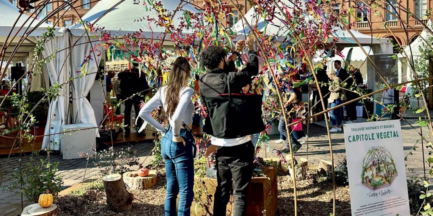 Capitole Végétal à Toulouse avec des visiteurs interagissant autour d'une installation végétale et de stands engagés pour l'écologie.